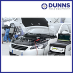 GYS GYSFLASH 100.12 HF battery support unit in use in a professional workshop, connected to a vehicle battery during diagnostic phase alongside a laptop